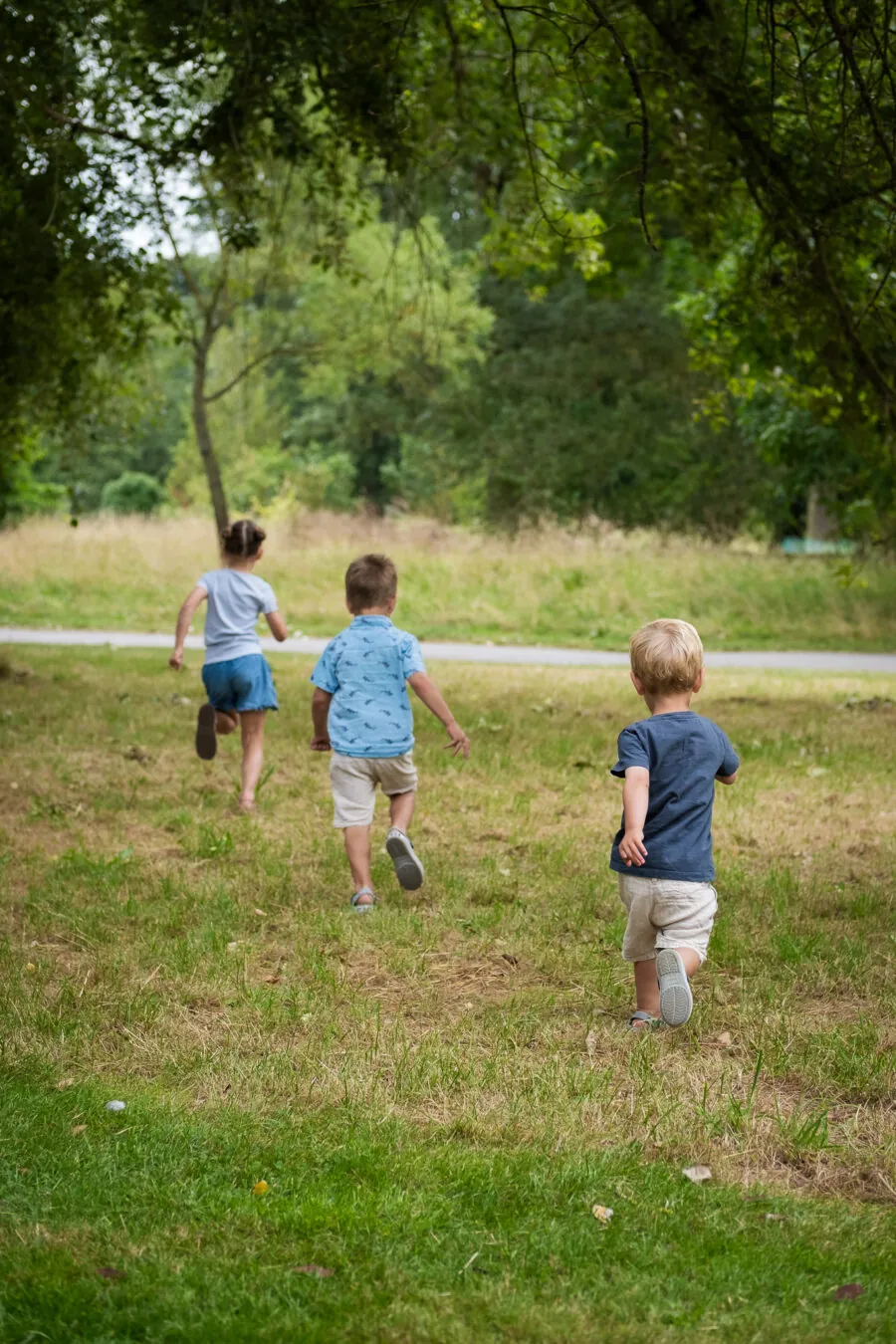 Three children running in a park, playing and having fun