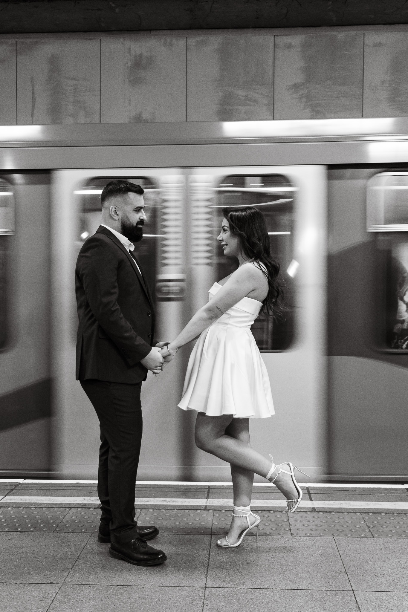 Couple holding hands while the underground train in London is passing by behind them
