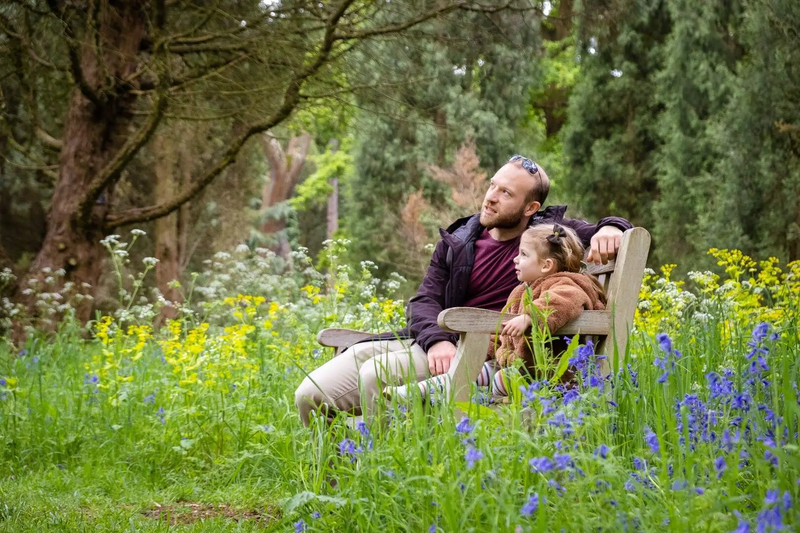Father and his daughter sitting on a bench in Kew gardens, looking at the beauty of nature, while having a photoshoot from Mellsnap