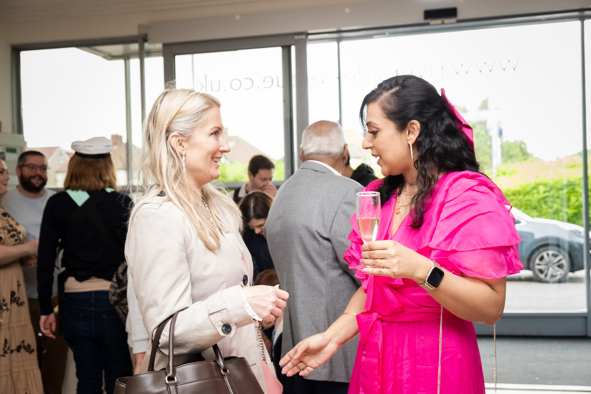 Two laddies talking, one of the holding a glass and probably making compliments on the other woman about her clothes