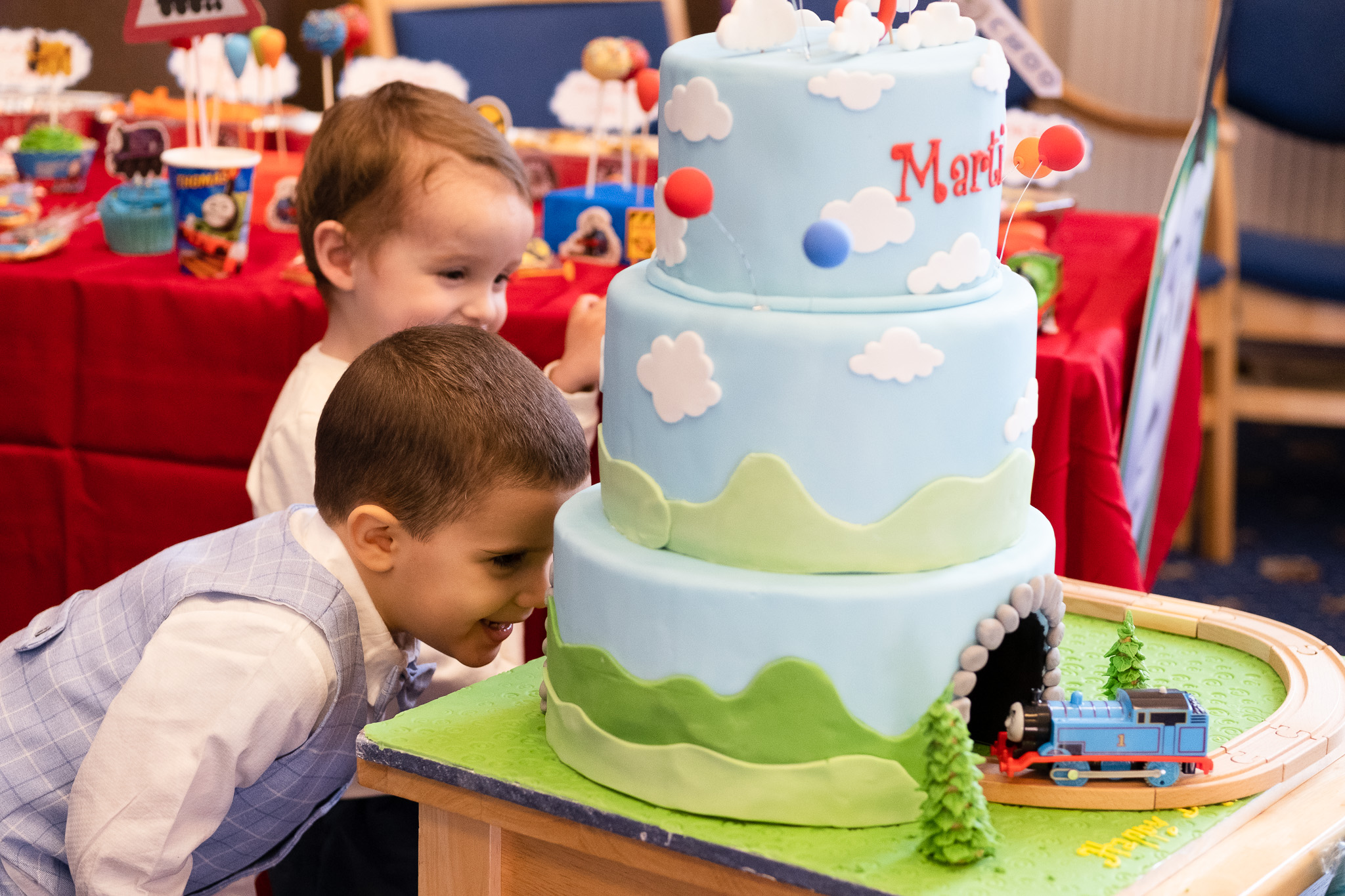 Two little boys looking for a small train coming from a birthday cake 
