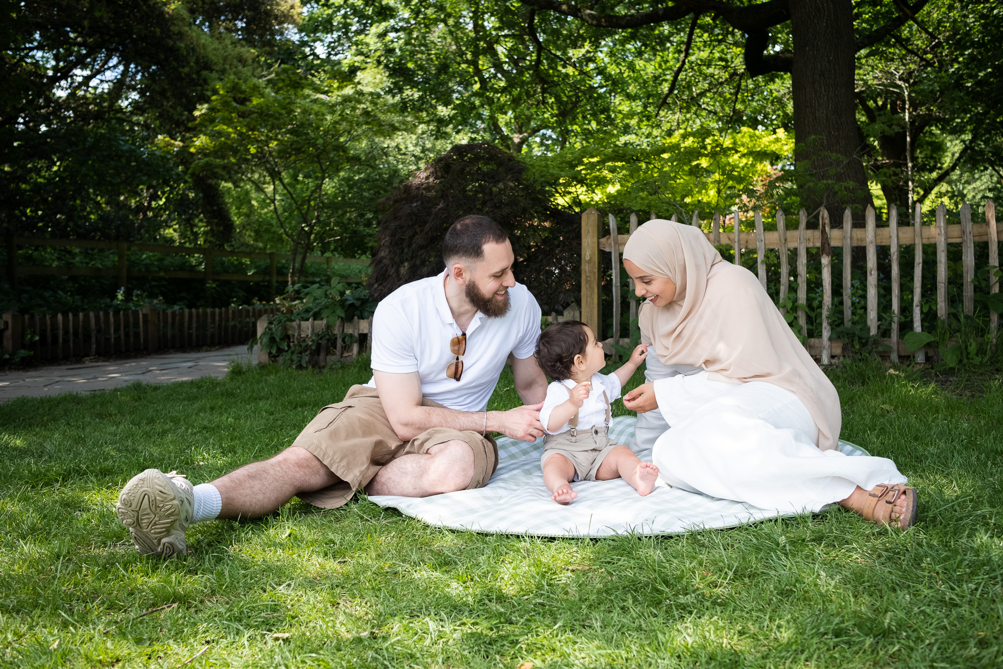 Family of three sitting on a picnic in park, celebrating their son's first birthday