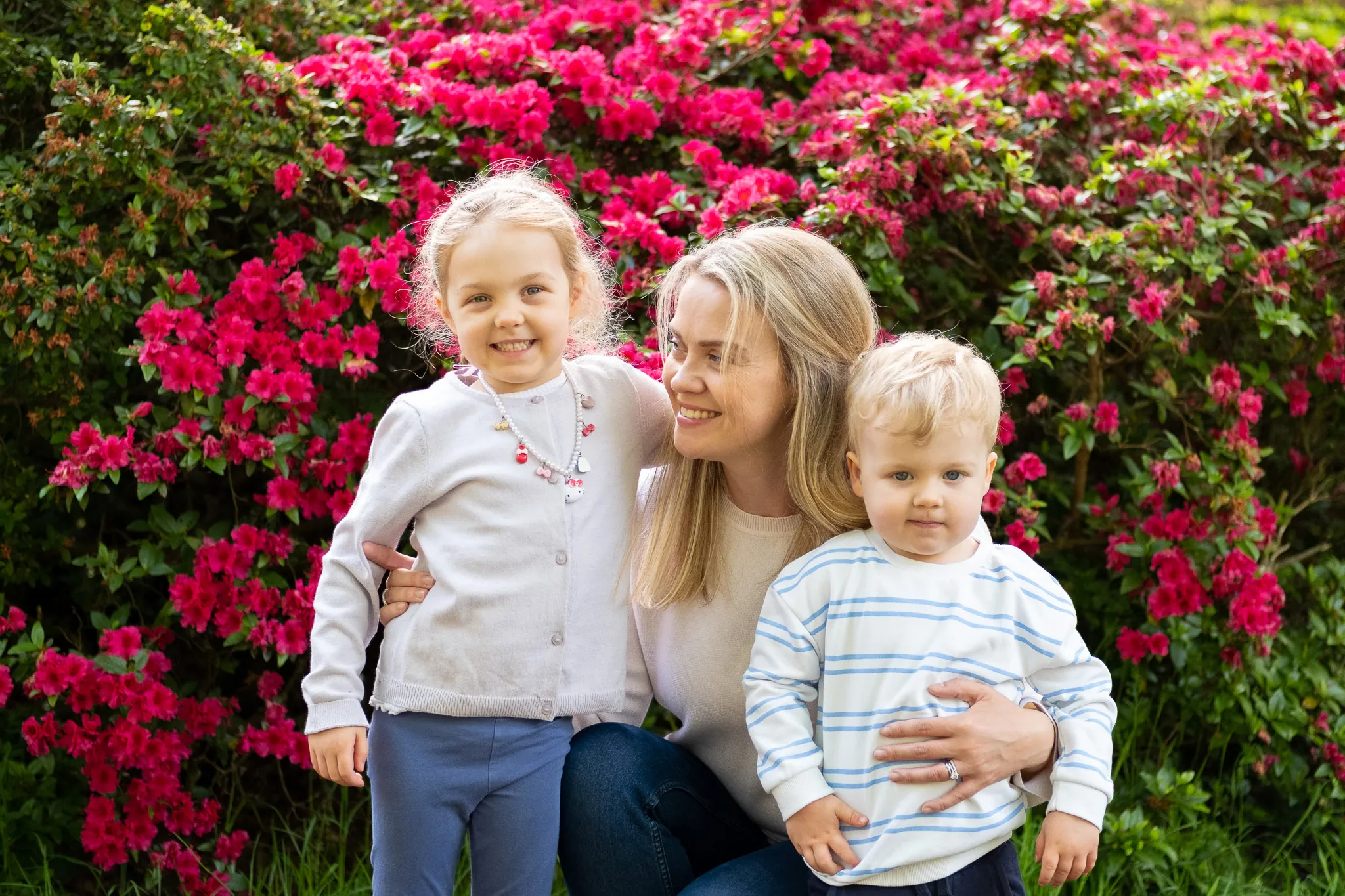 mum with her children hugging and smilling, posing for a family photoshoot at Isabella plantation in Richmond park