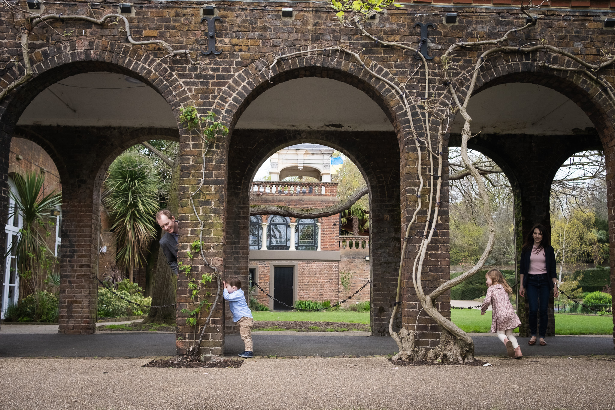 Family of four playing hide and seek in Holland park